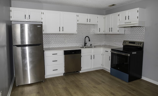 kitchen with under cabinet range hood, stainless steel appliances, a sink, white cabinets, and light countertops