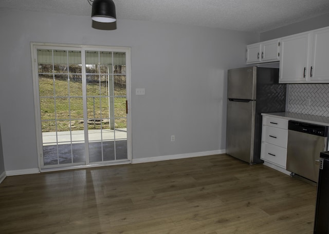 kitchen with tasteful backsplash, white cabinets, appliances with stainless steel finishes, wood finished floors, and a textured ceiling