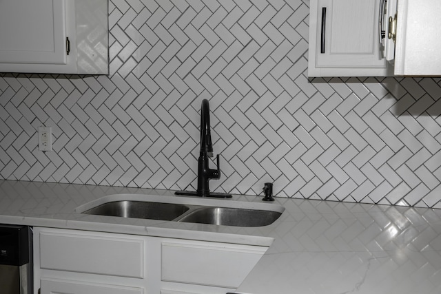 kitchen featuring dishwashing machine, white cabinetry, light countertops, and a sink