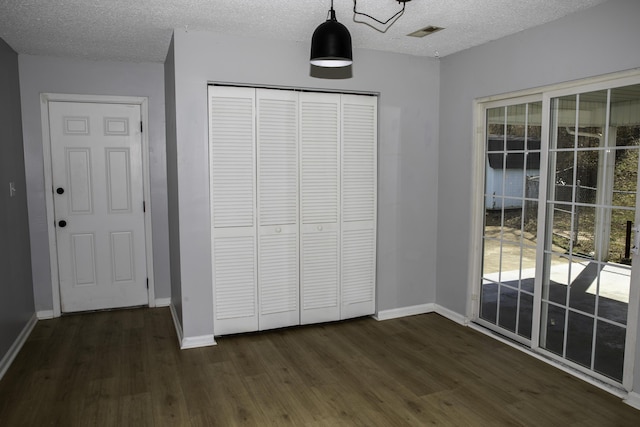 unfurnished bedroom featuring a closet, multiple windows, and dark wood finished floors