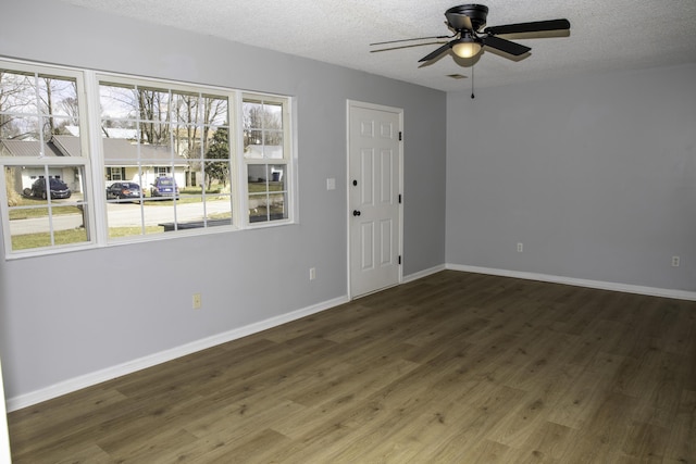 empty room with a textured ceiling, ceiling fan, wood finished floors, and baseboards