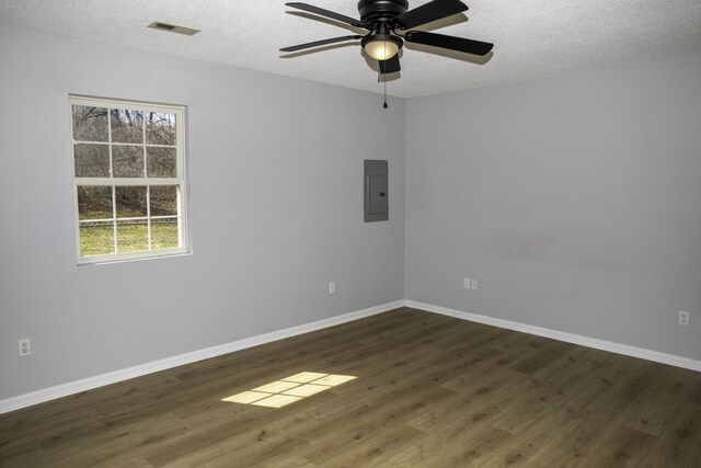 spare room featuring visible vents, a textured ceiling, dark wood-style floors, and electric panel