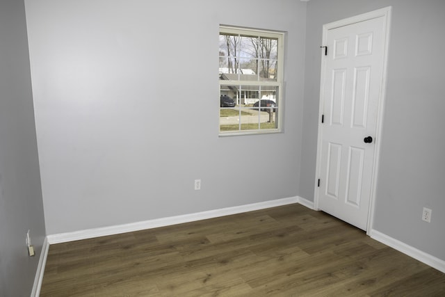 unfurnished room featuring dark wood-style flooring and baseboards