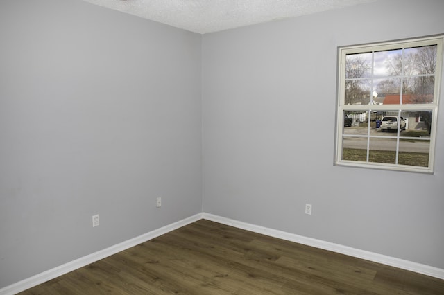 spare room with dark wood-style floors, a textured ceiling, and baseboards