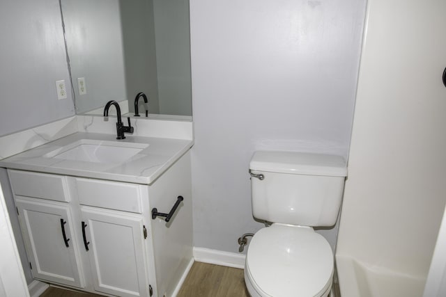 bathroom featuring toilet, baseboards, wood finished floors, and vanity