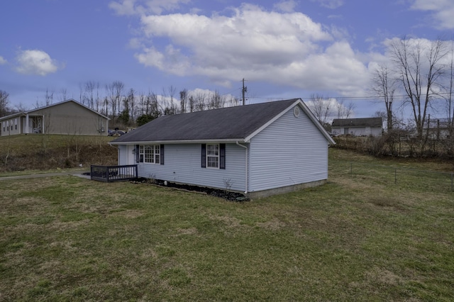 rear view of house with a shingled roof, fence, and a lawn