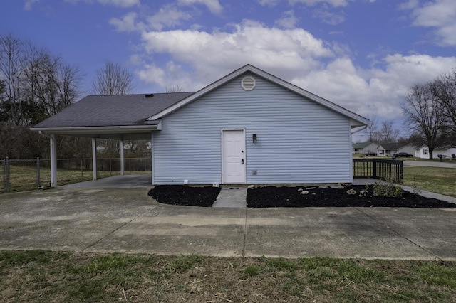 exterior space with a shingled roof, an attached carport, fence, and driveway