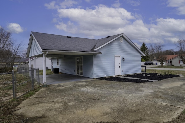 exterior space with driveway, a shingled roof, fence, and central AC