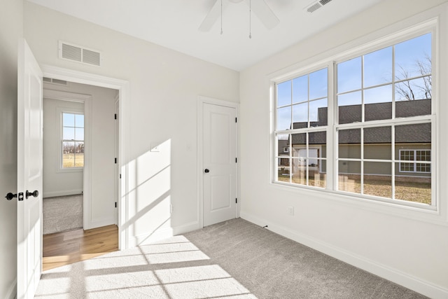 unfurnished room with light carpet, visible vents, and baseboards