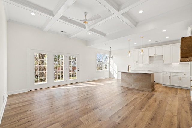 kitchen featuring beam ceiling, tasteful backsplash, white cabinets, light wood-type flooring, and coffered ceiling