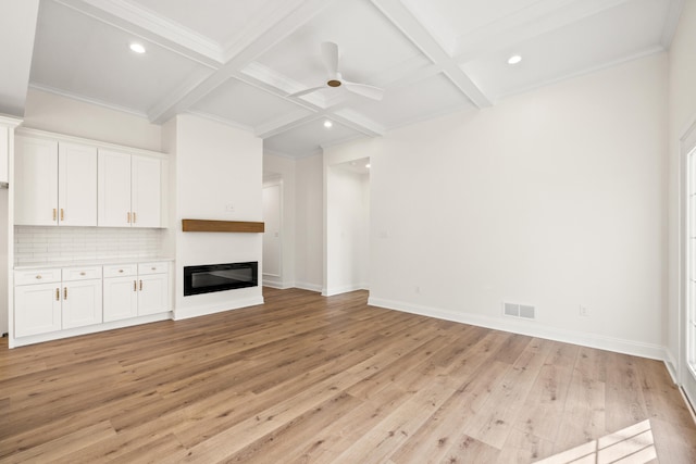 unfurnished living room with light wood finished floors, beamed ceiling, coffered ceiling, and visible vents