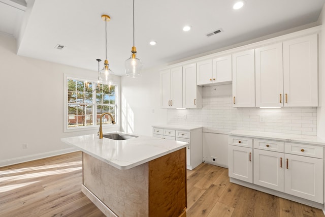 kitchen with decorative backsplash, light wood-style floors, white cabinetry, a sink, and recessed lighting