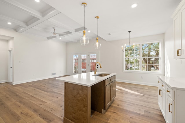 kitchen featuring coffered ceiling, light wood-style flooring, beamed ceiling, a sink, and recessed lighting