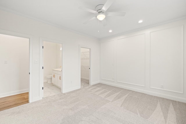 unfurnished bedroom featuring light carpet, a decorative wall, and ensuite bathroom