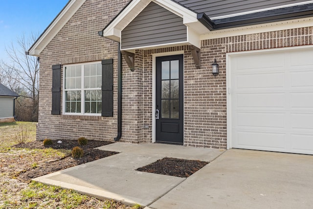 property entrance featuring an attached garage and brick siding