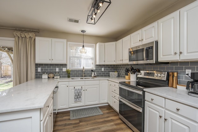 kitchen with stainless steel appliances, a sink, visible vents, white cabinets, and dark wood-style floors