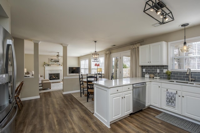 kitchen with a fireplace, a sink, appliances with stainless steel finishes, decorative backsplash, and dark wood-style floors