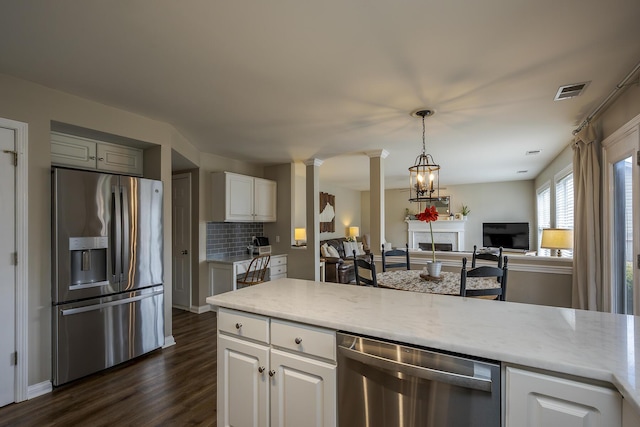 kitchen featuring a fireplace, white cabinetry, appliances with stainless steel finishes, dark wood finished floors, and decorative columns