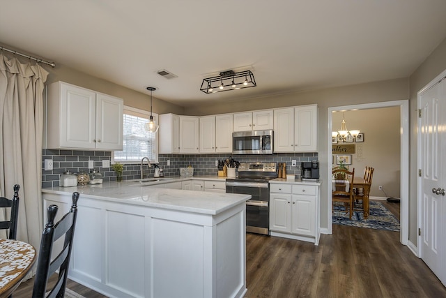 kitchen featuring a peninsula, a sink, visible vents, white cabinetry, and appliances with stainless steel finishes