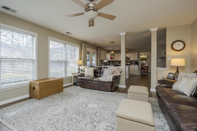 living area featuring dark wood-style floors, visible vents, baseboards, and ceiling fan with notable chandelier