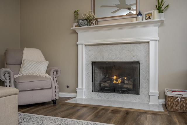 details featuring a tile fireplace, baseboards, and wood finished floors