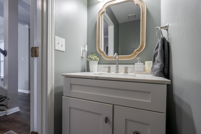 bathroom featuring baseboards, visible vents, wood finished floors, and vanity