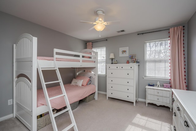 bedroom with light carpet, ceiling fan, visible vents, and baseboards