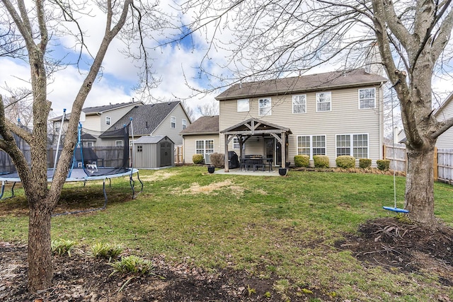 back of property with a trampoline, an outbuilding, a patio, a shed, and a fenced backyard