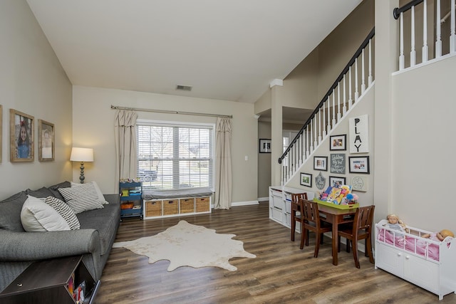 living room featuring baseboards, visible vents, stairway, and wood finished floors