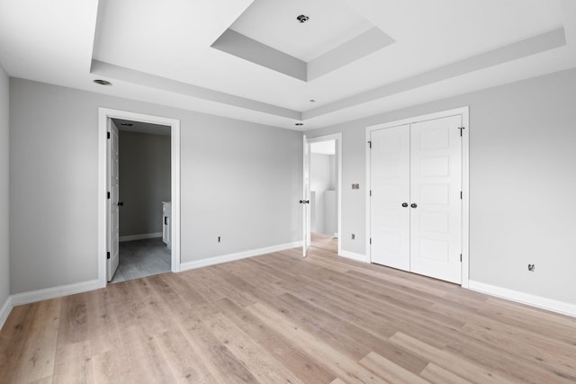 1000 Indian Trl, Lawrenceburg, KY 40342 - unfurnished bedroom featuring a tray ceiling, baseboards, connected bathroom, and light wood finished floors
