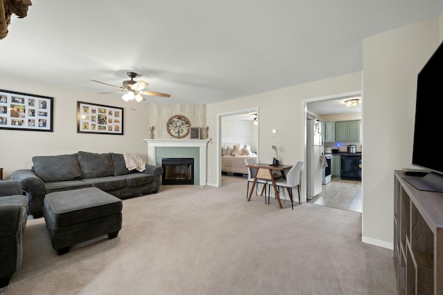 living area with light carpet, ceiling fan, and a tile fireplace