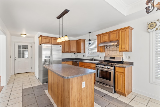 kitchen featuring dark countertops, under cabinet range hood, light tile patterned flooring, stainless steel appliances, and a sink