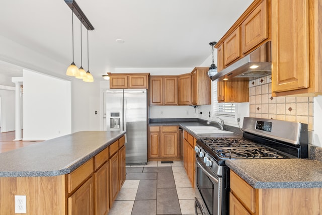 kitchen featuring a sink, stainless steel appliances, under cabinet range hood, dark countertops, and a center island