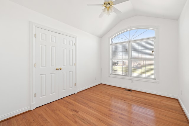 unfurnished bedroom featuring visible vents, ceiling fan, baseboards, lofted ceiling, and light wood-style floors