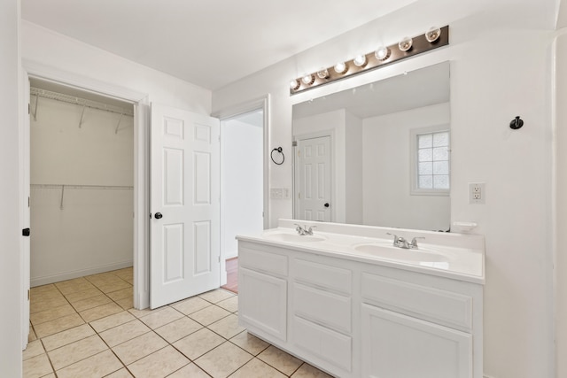 bathroom with double vanity, a spacious closet, tile patterned floors, and a sink