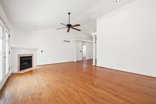 unfurnished living room with ceiling fan, baseboards, lofted ceiling, a fireplace, and light wood-style floors