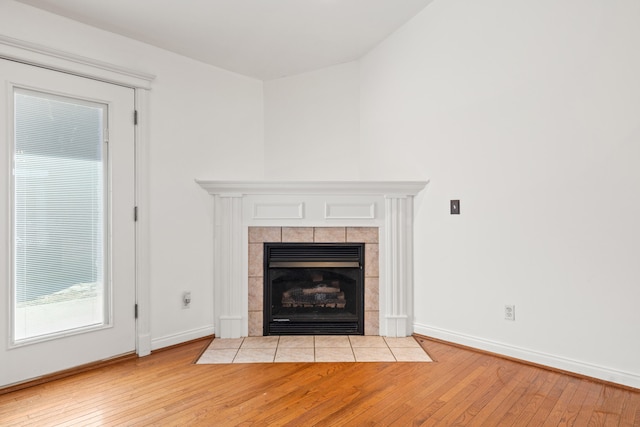 details featuring baseboards, wood finished floors, and a tiled fireplace