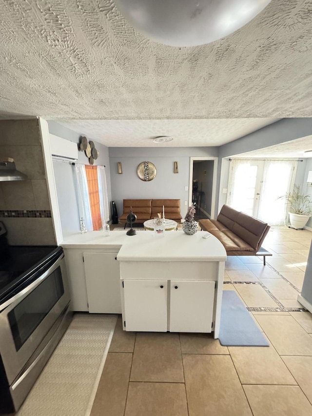 kitchen with electric range, white cabinets, a wall unit AC, light countertops, and under cabinet range hood