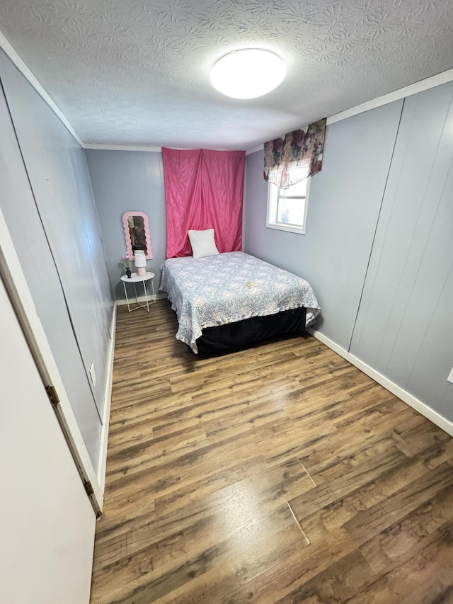 bedroom with a textured ceiling, wood finished floors, and baseboards