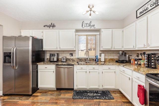 kitchen featuring white cabinets, decorative backsplash, stainless steel appliances, and a sink