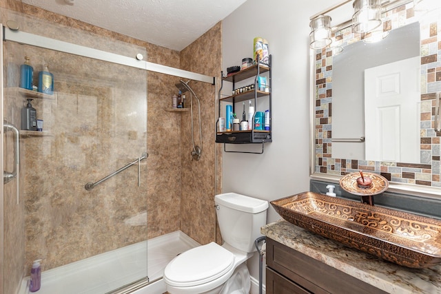 full bath with toilet, a stall shower, a textured ceiling, and vanity