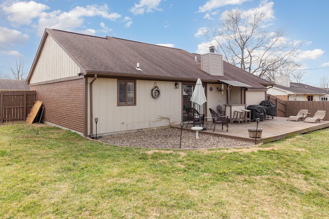 rear view of house with a chimney, brick siding, a lawn, and a fenced backyard