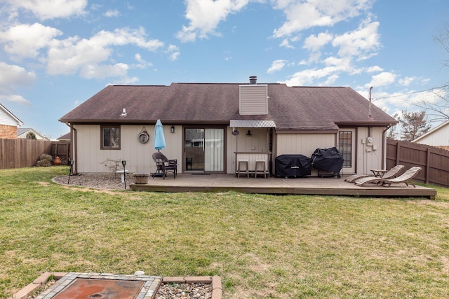 rear view of property featuring a lawn, a chimney, a fenced backyard, and a wooden deck