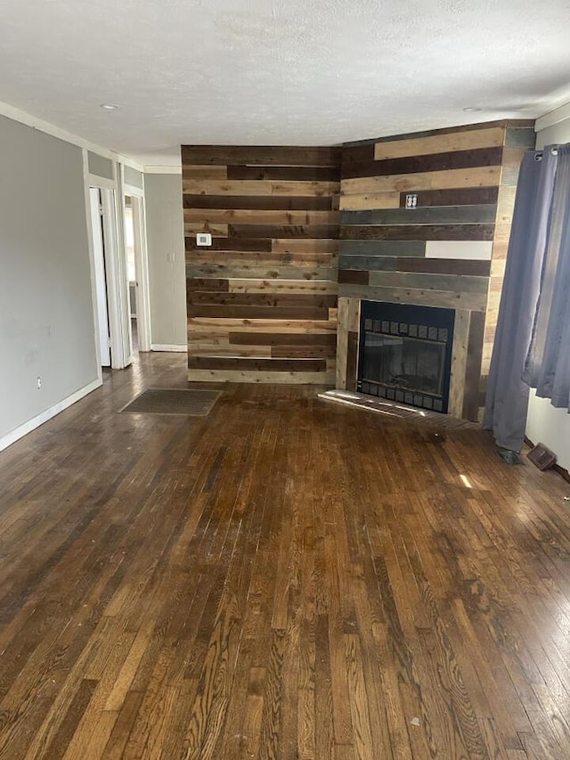 unfurnished living room featuring a glass covered fireplace, baseboards, wood-type flooring, and a textured ceiling