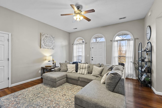 living area with dark wood-type flooring, baseboards, visible vents, and ceiling fan