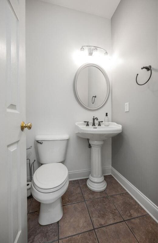 half bath featuring tile patterned flooring, toilet, and baseboards