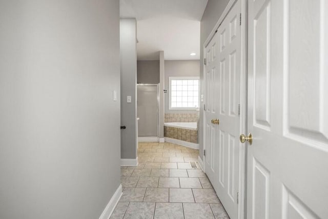 bathroom with a stall shower, tile patterned flooring, a bath, and baseboards