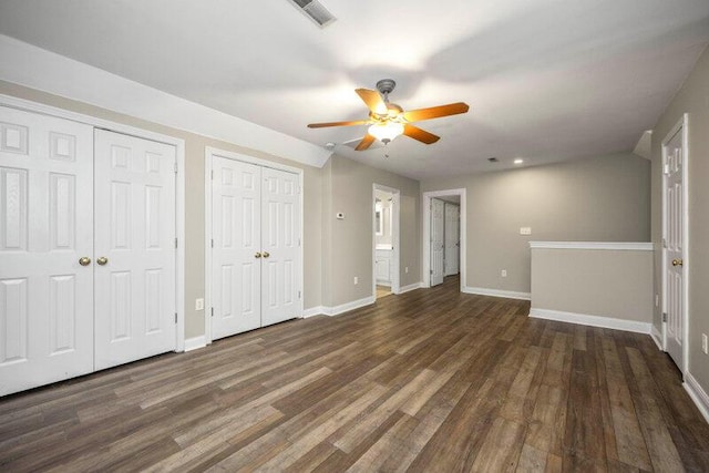 unfurnished bedroom with baseboards, visible vents, two closets, and wood finished floors