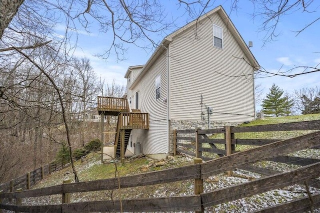 view of side of property featuring stairway, fence, and a wooden deck