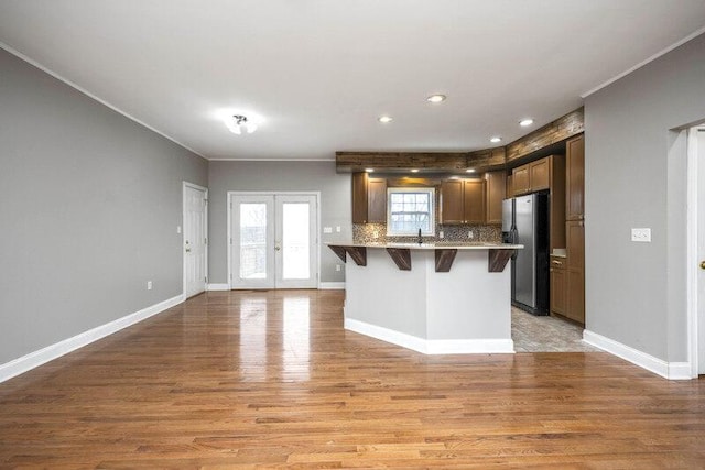 kitchen with light wood-type flooring, a kitchen breakfast bar, french doors, and stainless steel fridge with ice dispenser